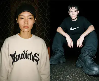 Model in white Vedicatus sweatshirt against chain-link fence.